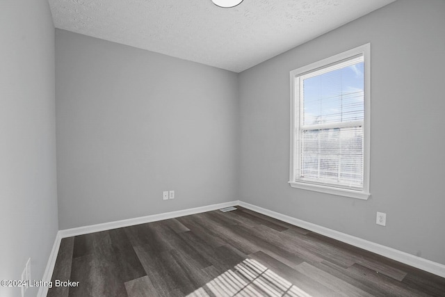 spare room with a wealth of natural light, dark wood-type flooring, and a textured ceiling