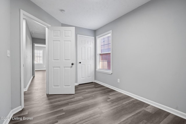 unfurnished bedroom with a textured ceiling, a closet, and dark wood-type flooring