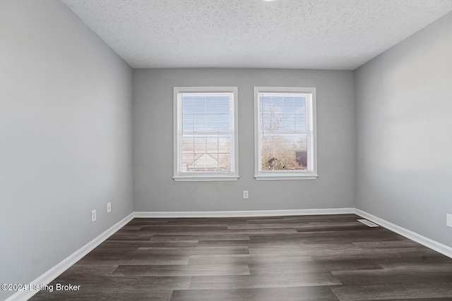 empty room with a textured ceiling and dark wood-type flooring