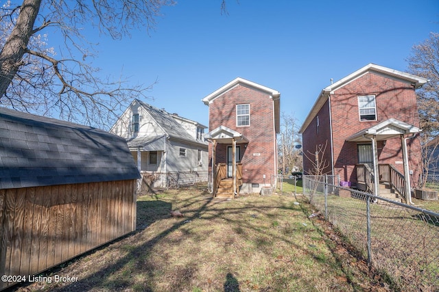 back of house featuring a lawn and a storage shed