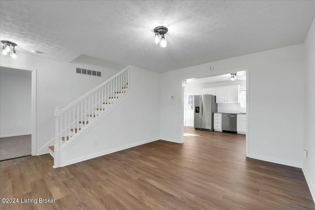 unfurnished living room featuring a textured ceiling and dark hardwood / wood-style floors