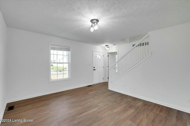 unfurnished room with hardwood / wood-style flooring and a textured ceiling