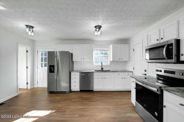 kitchen with dark hardwood / wood-style flooring, sink, white cabinets, and stainless steel appliances