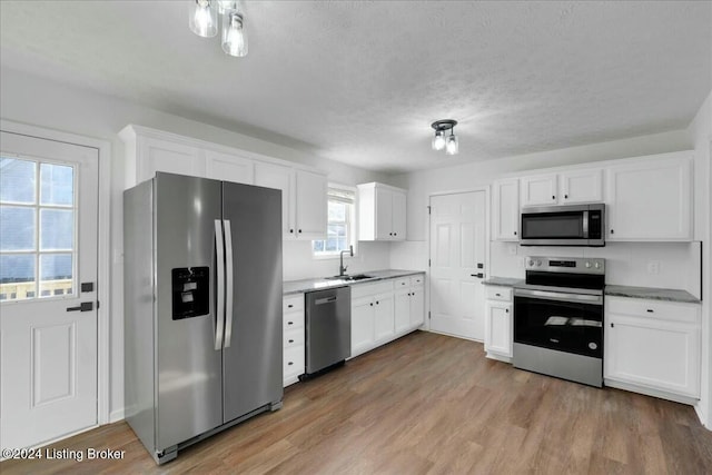 kitchen featuring wood-type flooring, stainless steel appliances, white cabinetry, and sink