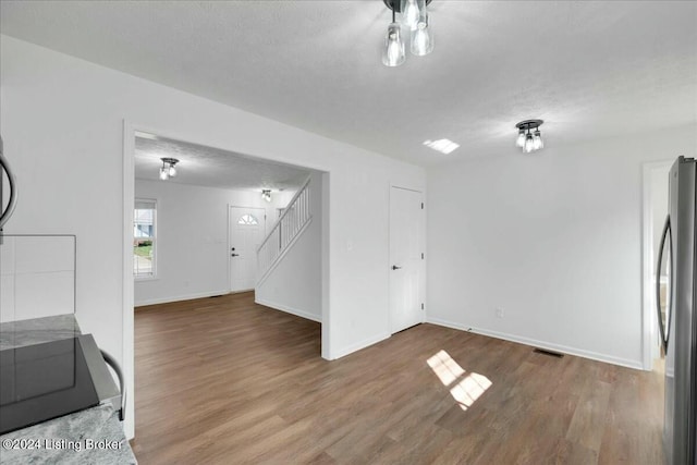 interior space with stainless steel fridge, a textured ceiling, and hardwood / wood-style flooring