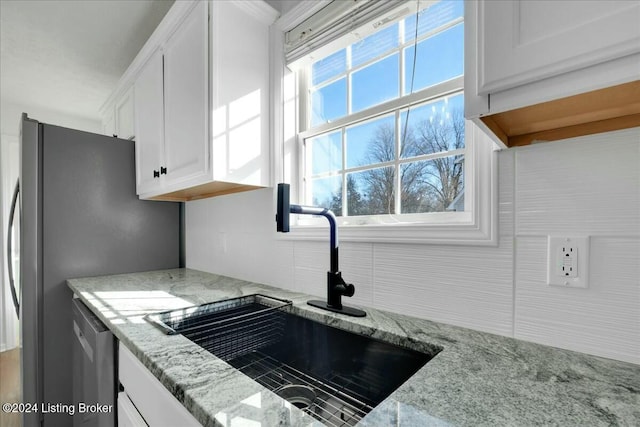 kitchen with light stone countertops, stainless steel appliances, white cabinetry, and sink