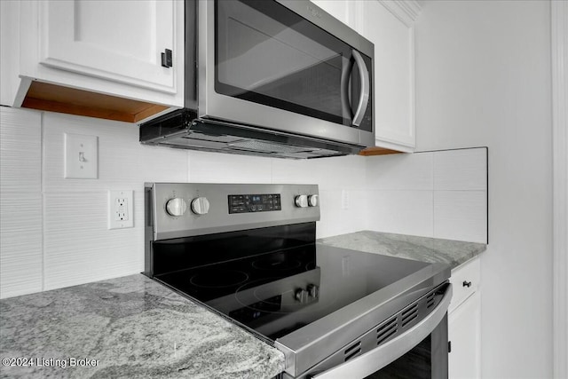 kitchen with white cabinets, appliances with stainless steel finishes, decorative backsplash, and light stone counters