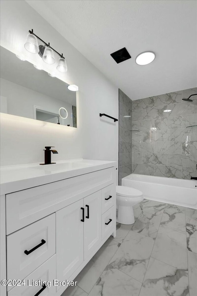 bathroom featuring a tile shower, vanity, and toilet