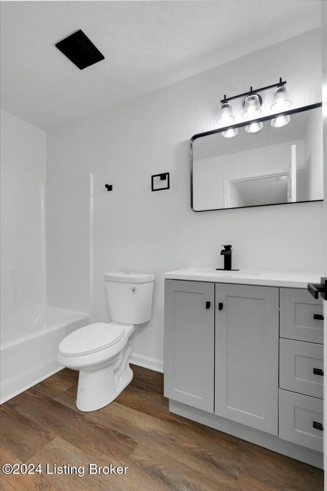 full bathroom featuring vanity, toilet, wood-type flooring, and a textured ceiling