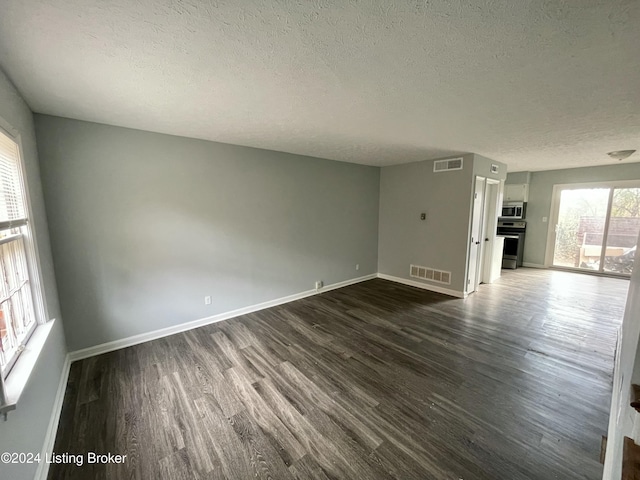 unfurnished living room featuring a textured ceiling and dark wood-type flooring