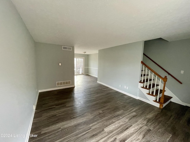 spare room featuring a textured ceiling and dark wood-type flooring