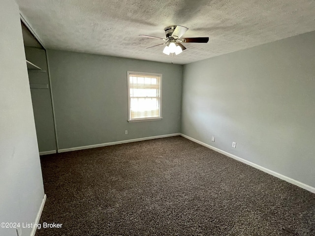 unfurnished bedroom with dark colored carpet, a textured ceiling, and ceiling fan