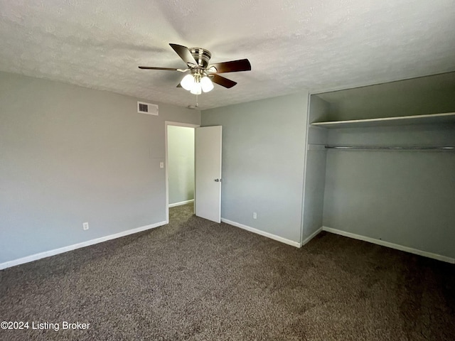 unfurnished bedroom featuring ceiling fan, a closet, dark carpet, and a textured ceiling