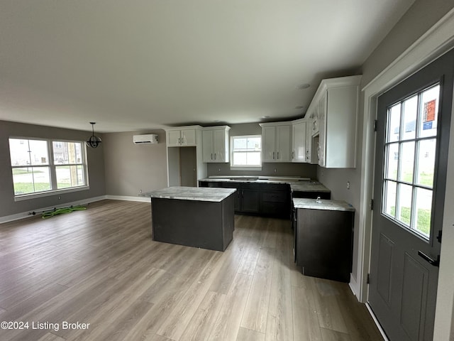 kitchen featuring white microwave, a kitchen island, white cabinetry, light countertops, and a wall mounted AC