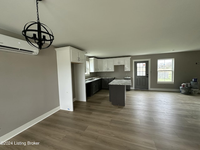 kitchen featuring dark wood-style flooring, open floor plan, white cabinets, a kitchen island, and baseboards