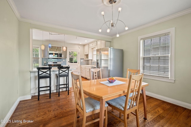 dining room with wood-type flooring, a healthy amount of sunlight, sink, and a notable chandelier