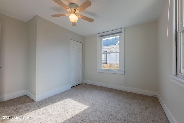 carpeted spare room featuring ceiling fan