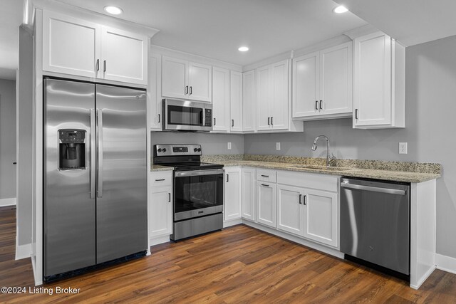 kitchen featuring white cabinets, sink, dark hardwood / wood-style floors, light stone counters, and stainless steel appliances