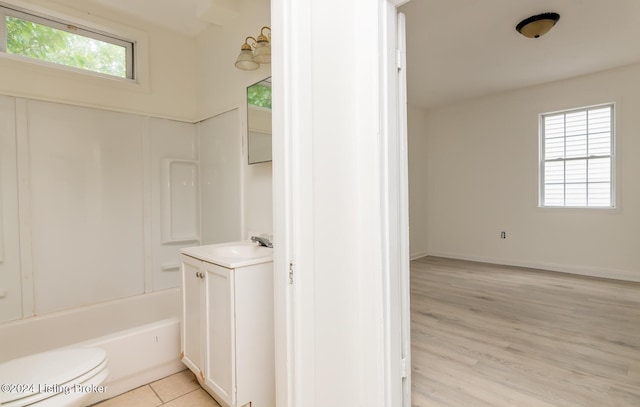 full bathroom featuring toilet, vanity, a healthy amount of sunlight, and hardwood / wood-style flooring