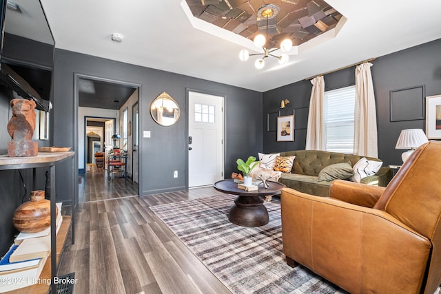 living room with dark wood-type flooring, a chandelier, and a tray ceiling