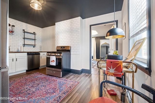 kitchen featuring decorative backsplash, white cabinets, decorative light fixtures, stainless steel appliances, and dark hardwood / wood-style floors