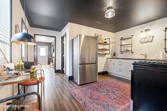 kitchen featuring white cabinetry, stainless steel refrigerator, range with gas cooktop, dark hardwood / wood-style flooring, and backsplash