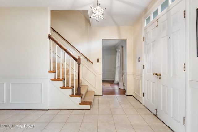 tiled entryway featuring ornamental molding and an inviting chandelier