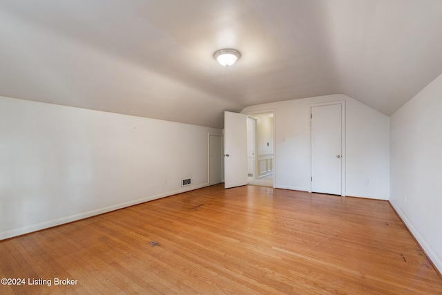 additional living space with light wood-type flooring and vaulted ceiling