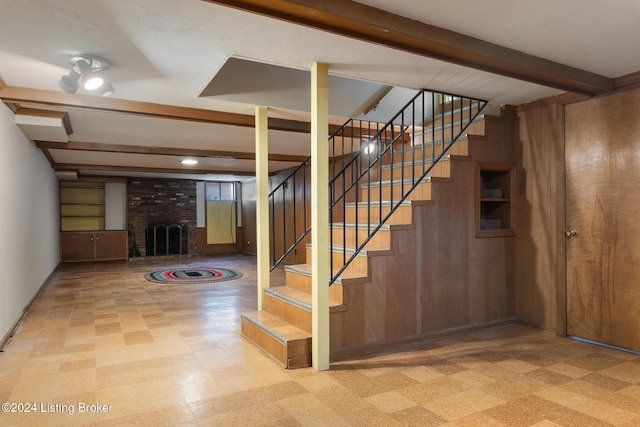 basement with wooden walls and a brick fireplace