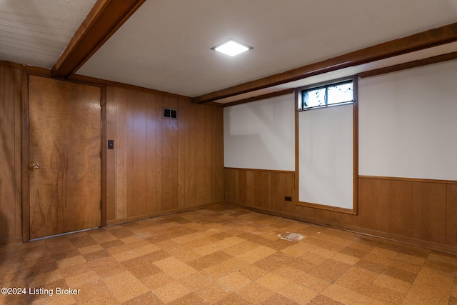 unfurnished room with wood walls and beamed ceiling