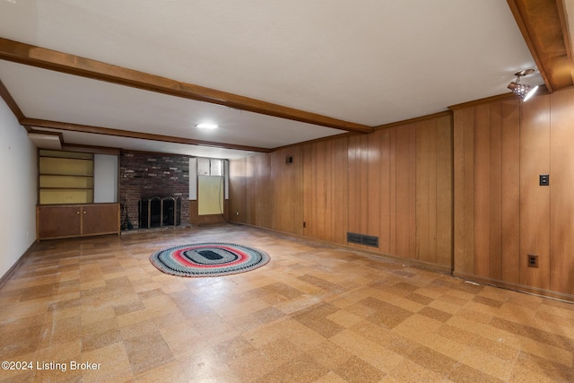 unfurnished living room featuring wooden walls, beamed ceiling, and a brick fireplace