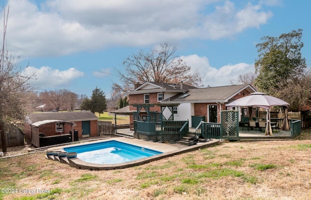 view of swimming pool featuring a gazebo, a shed, a deck, and a lawn