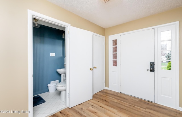 entryway featuring a textured ceiling and light hardwood / wood-style flooring