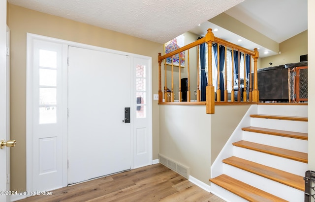 foyer with a healthy amount of sunlight, light wood-type flooring, and a textured ceiling