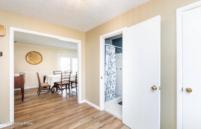 corridor with light hardwood / wood-style floors and a textured ceiling