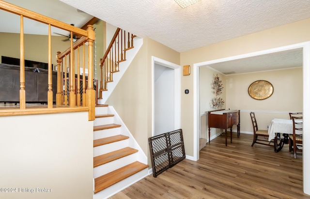 staircase with wood-type flooring and a textured ceiling