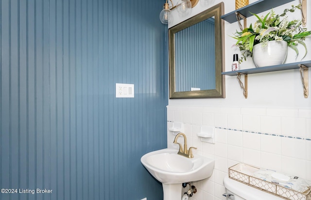 bathroom featuring toilet, sink, and tile walls