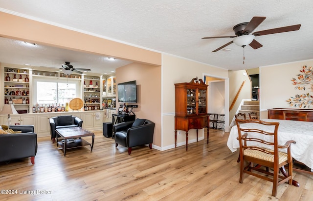 living area featuring a textured ceiling, light hardwood / wood-style flooring, ceiling fan, and ornamental molding