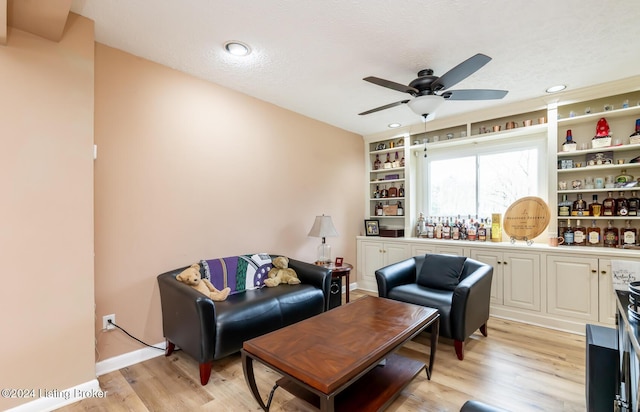 living room featuring ceiling fan, a textured ceiling, and light wood-type flooring