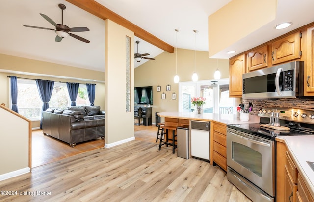 kitchen with light wood-type flooring, appliances with stainless steel finishes, beamed ceiling, decorative light fixtures, and a kitchen bar