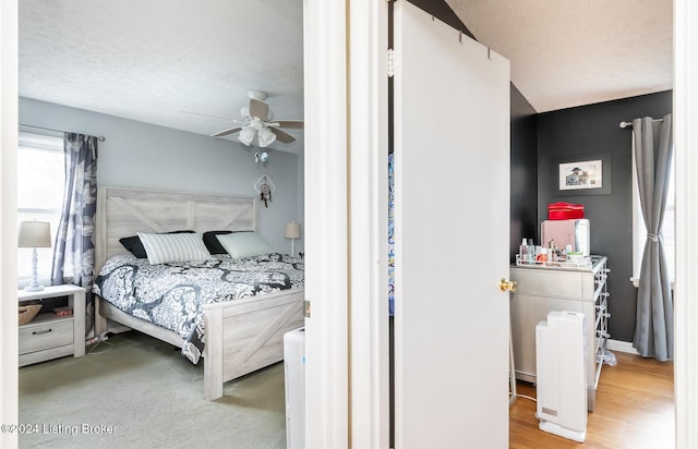 bedroom with ceiling fan, a textured ceiling, and light hardwood / wood-style flooring