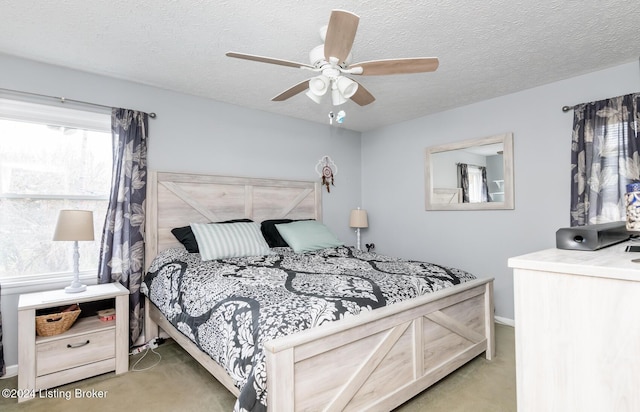 bedroom with ceiling fan, light colored carpet, and a textured ceiling