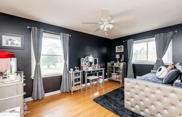 bedroom with multiple windows, ceiling fan, a textured ceiling, and hardwood / wood-style flooring