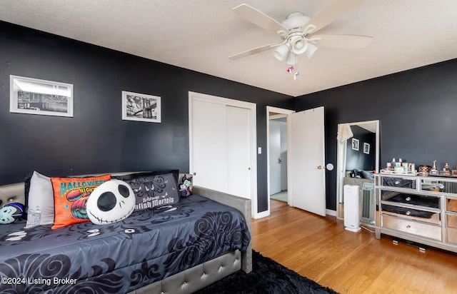 bedroom featuring ceiling fan, wood-type flooring, a textured ceiling, and a closet