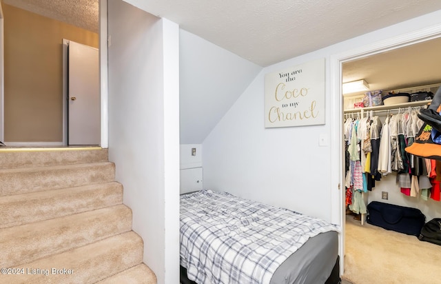 carpeted bedroom with vaulted ceiling, a closet, and a textured ceiling