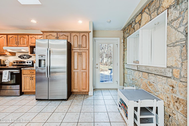 kitchen with light tile patterned floors, a skylight, and stainless steel appliances