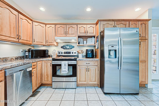 kitchen featuring light stone counters, light tile patterned floors, a healthy amount of sunlight, and appliances with stainless steel finishes