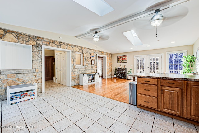 kitchen with lofted ceiling with skylight, light tile patterned floors, ceiling fan, and french doors