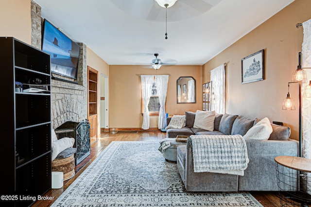 living room featuring hardwood / wood-style floors, a fireplace, ceiling fan, and built in shelves