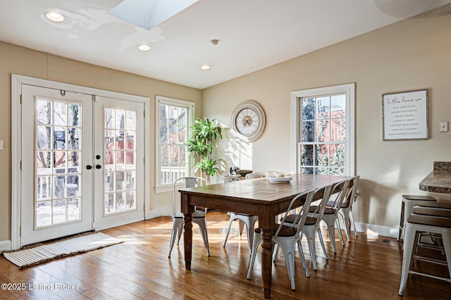 dining room with french doors, hardwood / wood-style flooring, and a skylight